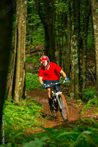 Mountain Biker Riding Down Forest Trail