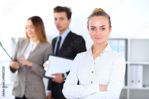 Pretty businesswoman in office with colleagues in the background