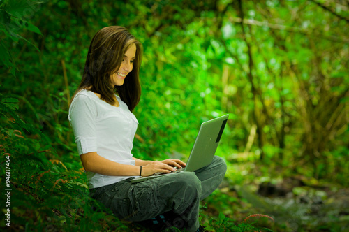 Beautiful young girl using laptop outdoors in the wild enjoying excellent connectivity