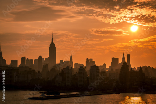 An orange sky sunrise behind a silhouette of Manhattan   s Skyline seen from the Hudson River