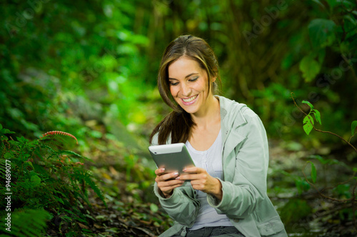 Beautiful young girl holding a tablet enjoying excellent connectivity in the jungle