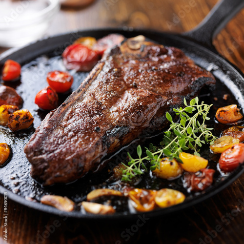 new york strip steak on iron skillet with heirloom tomatoes