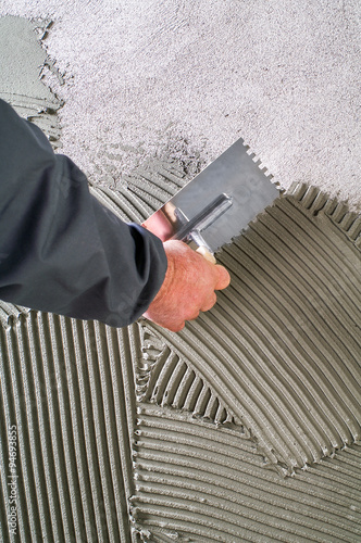 Billede på lærred Construction notched trowel with grey cement mortar for tiles wo