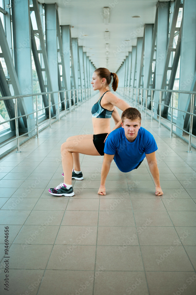 young man and woman doing exercises in the modern bridge construction young man and woman doing exercises in the modern bridge construction