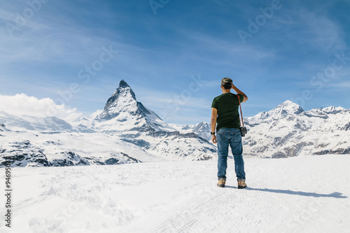 A man standing on the snow looking at the background of Matterho