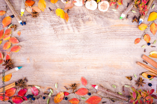 Colorful autumn leaves, spices, cinnamon, cloves, cardamom, anise and pensils lying on wooden background. Fall and thanksgiving setting. Autumn composition. Free space for text
