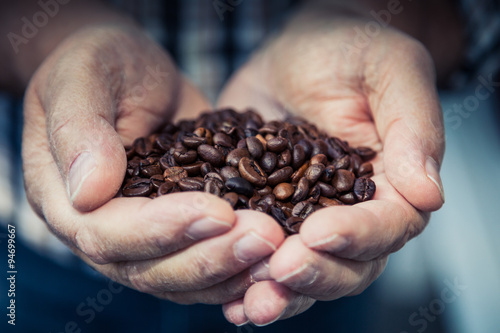 Hands holding pile of roasted coffee beans