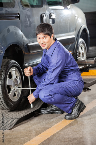 Confident Mechanic Fixing Car Tire With Rim Wrench