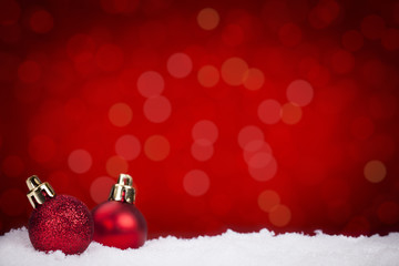 Red Christmas baubles on snow with a red background