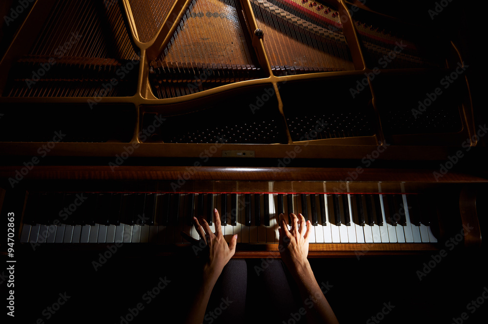 Obraz premium Ręce kobiety na klawiaturze fortepianu w nocy zbliżenie