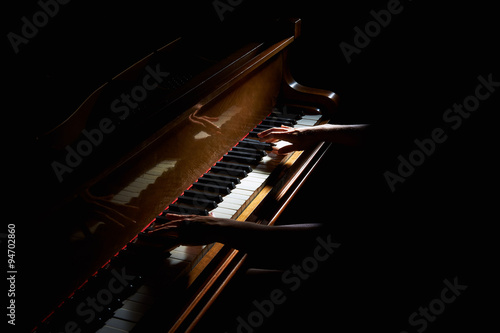 Woman's hands on the keyboard of the piano in night closeup