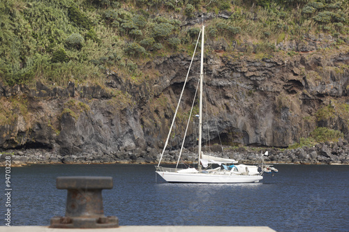 Anchored sailboat in Flores island port entrance. Azores, Portug