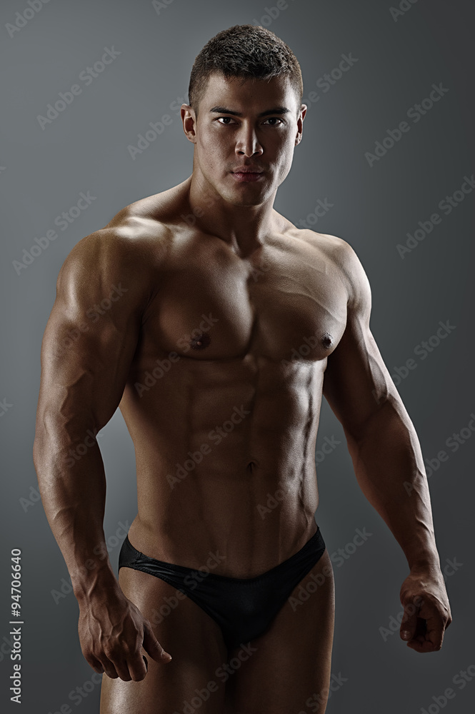 Portrait of a handsome muscular man standing over gray background. 