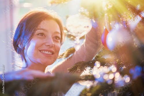 close up of a woman hanging a crystal ball in christmas tree