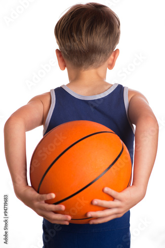 The boy held a basketball ball behind the back.