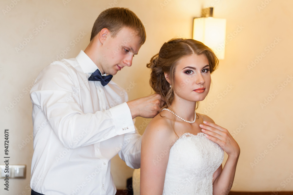 Groom hanging necklace on bride`s neck