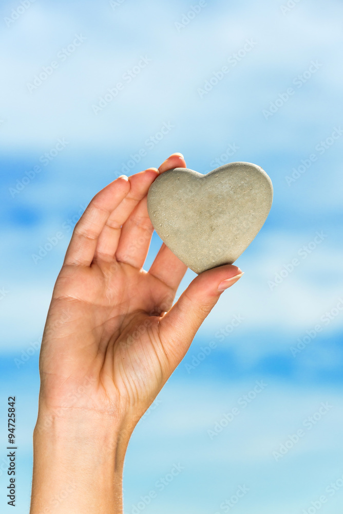 Heart held by hand against blue sky Heart held by hand against blue sky