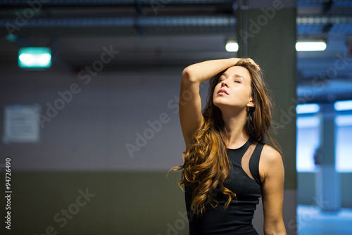 Fashion portrait of beautiful young woman inside garage.