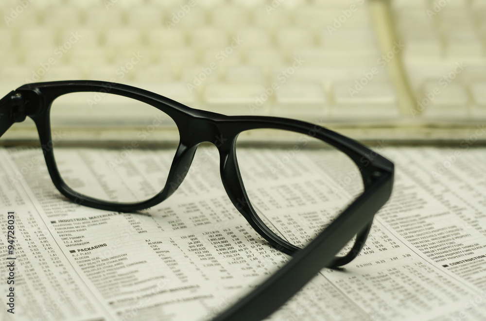 keyboard and a black eyeglasses on a financial newspaper keyboard and a black eyeglasses on a financial newspaper