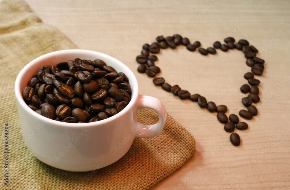 Obraz premium cup of coffee beans with heart coffee beans on the table