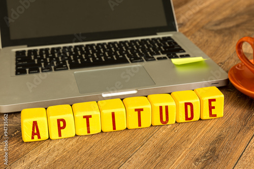 Aptitude written on a wooden cube in front of a laptop