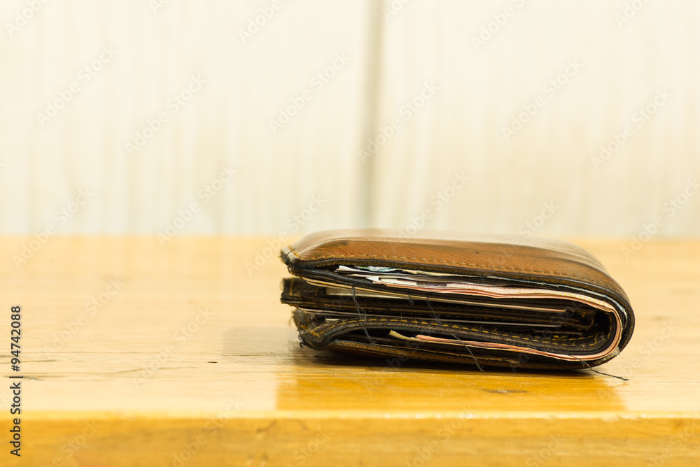 brown leather men's wallet with bank notes on brown wood texture brown leather men's wallet with bank notes on brown wood texture