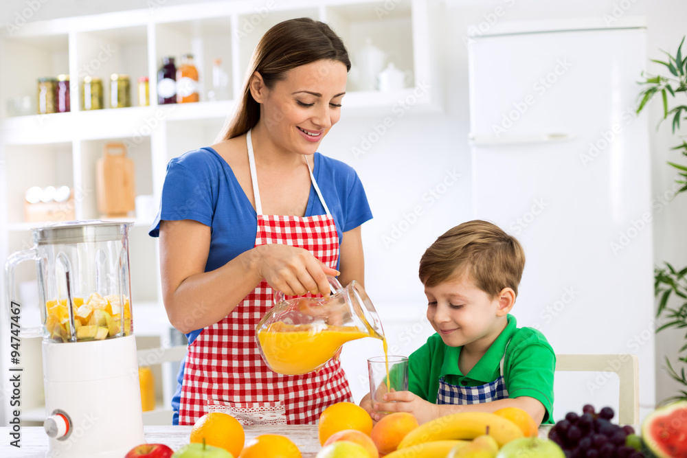 Young mother and child prepare fruits juice