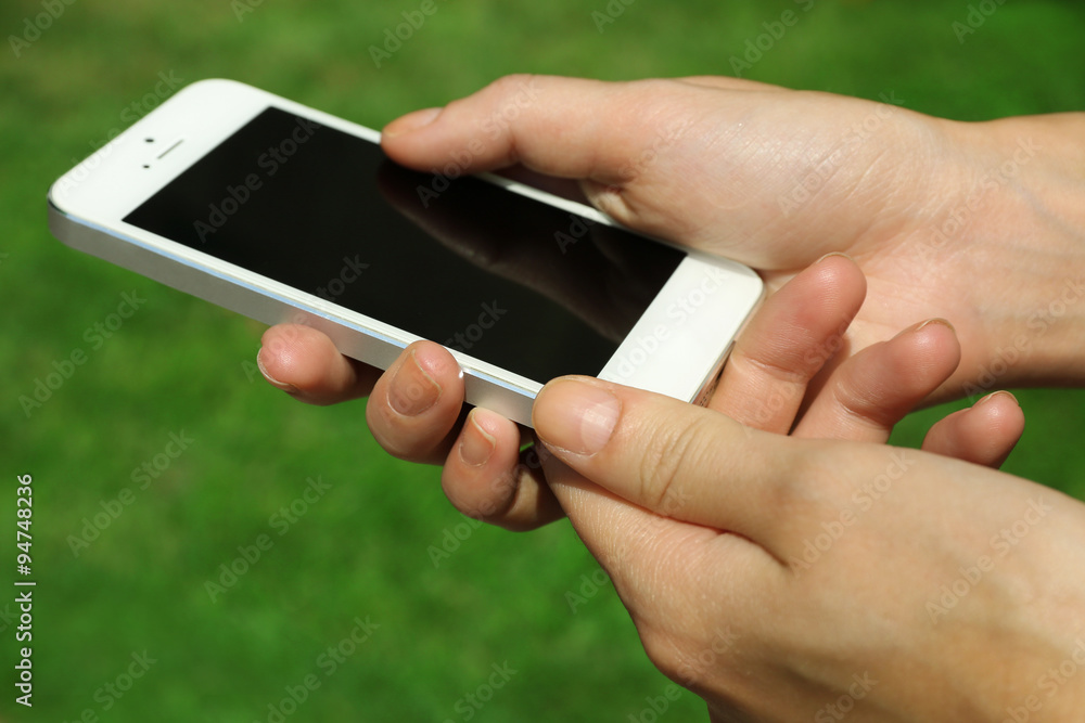 Female hands holding smart mobile phone outdoors