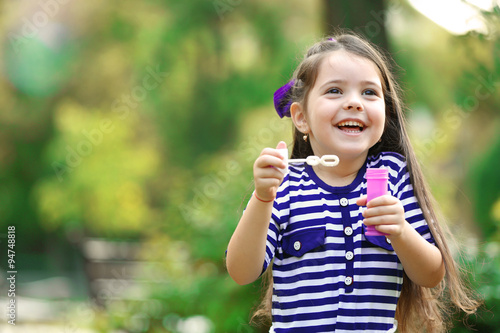 Happy little girl with bubbles in the park