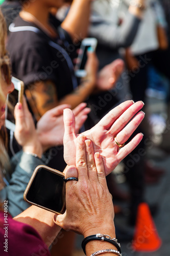 Frau in der Menschenmenge klatscht mit Smartphone in der Hand
