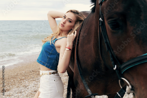 beautiful woman with blond hair posing with black horse