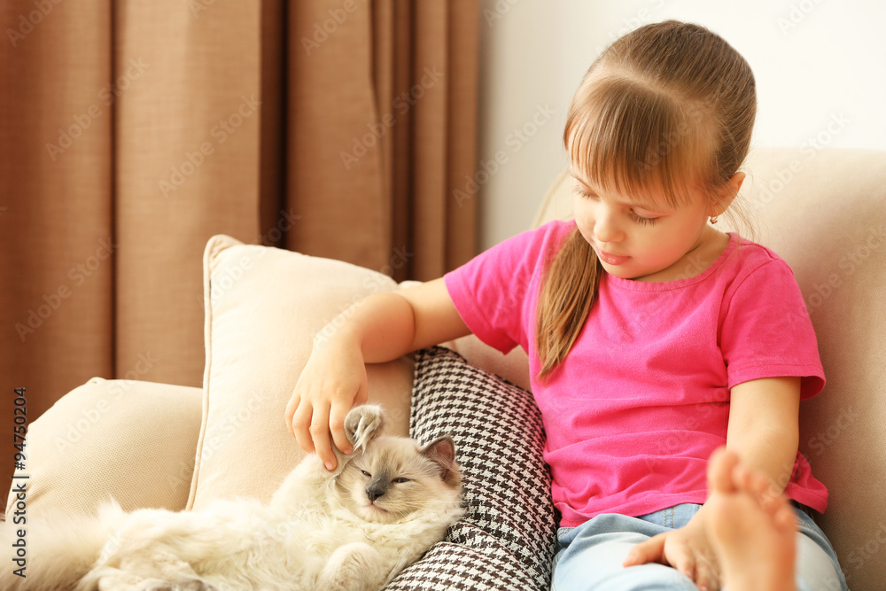 Little cute girl with kitten on sofa at home Little cute girl with kitten on sofa at home
