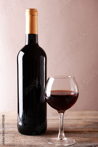 A bottle of red wine and a glass on wooden table