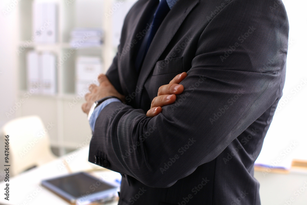 Obraz premium Smiling middle aged businessman in a shirt and tie standing in a modern office building with his arms crossed