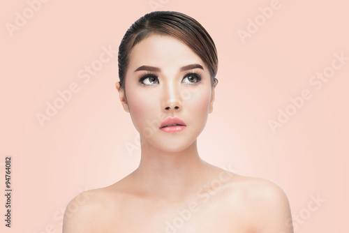 Beauty Asian Woman face Portrait. Beautiful Spa model Girl with Perfect Fresh Clean Skin. looking up. Youth and Skin Care Concept. on pink background with clipping path