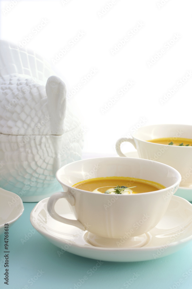 Traditional Thanksgiving pumpkin soup on pale blue table.