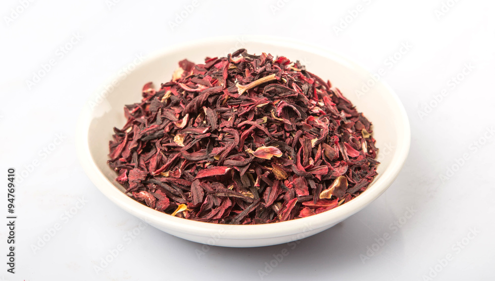 Dried red hibiscus tea leaves in white bowl over white background Dried red hibiscus tea leaves in white bowl over white background