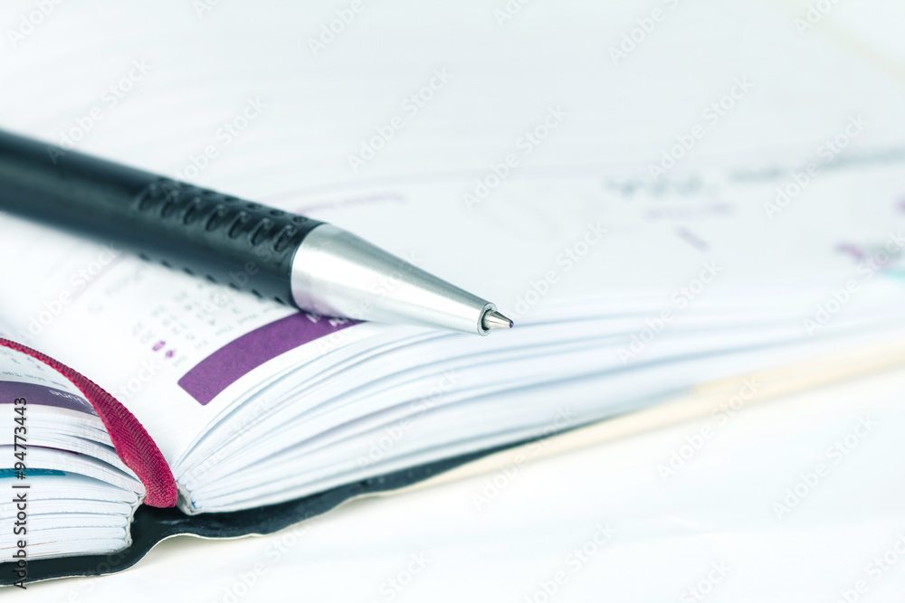 selective focus of ball pen on opened lined diary book with cale selective focus of ball pen on opened lined diary book with cale