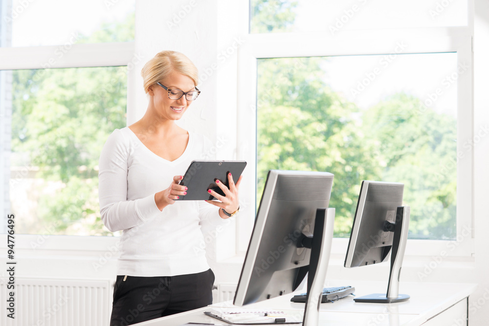 Attractive and happy female manager in office with a tablet. Attractive and happy female manager in office with a tablet.