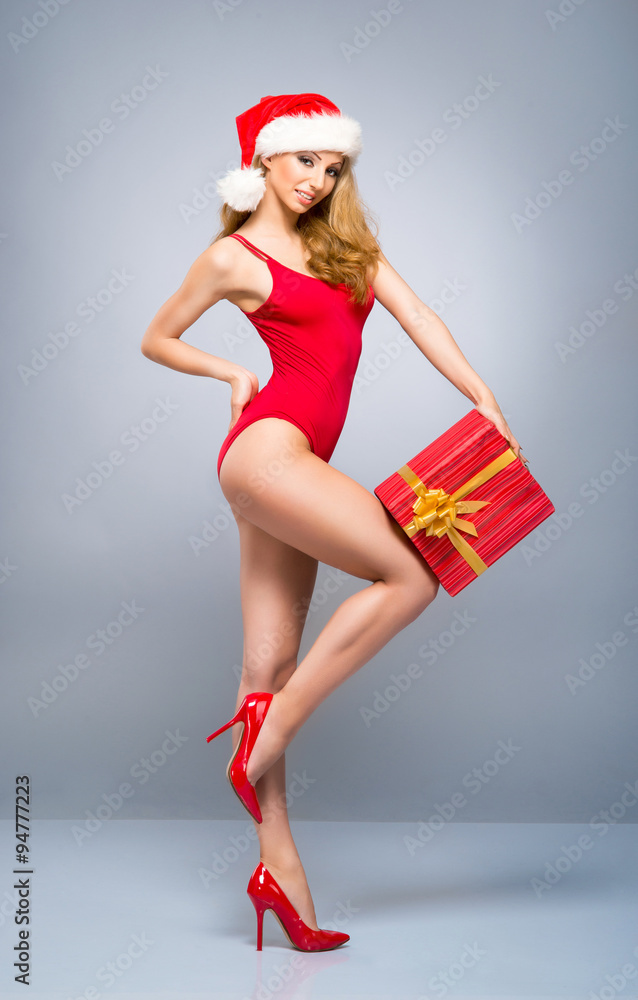 Young and sexy Santa girl in a red swimsuit with a Christmas present