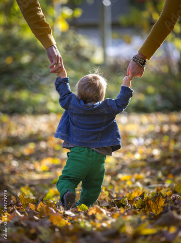 Kleinkind mit Eltern beim Spaziergang im Herbst