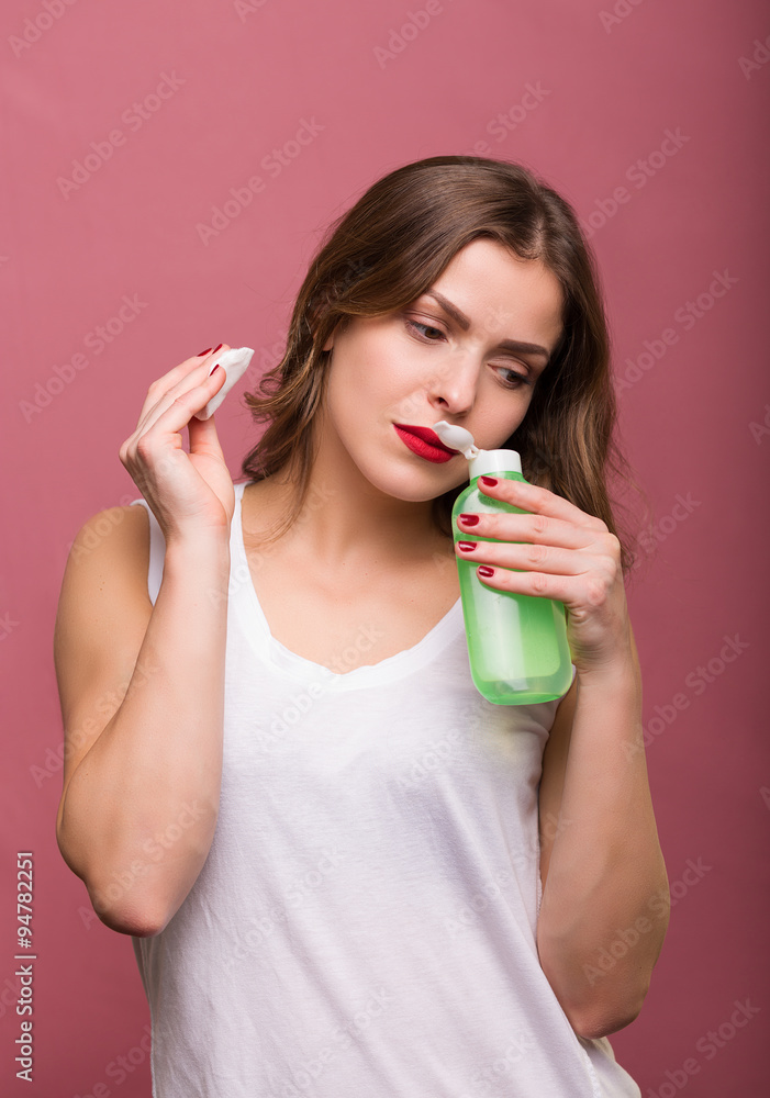 Woman holding a lotion and a cotton pad Woman holding a lotion and a cotton pad