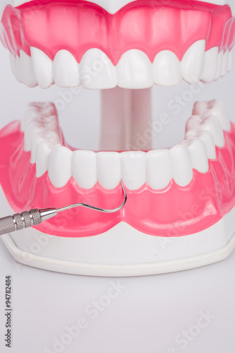 White teeth and dental instruments on white background