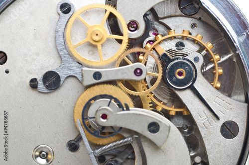 Metal cogwheels inside clockwork. Conceptual macro photo.