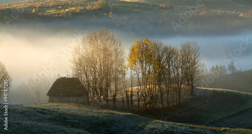 Small cottage in the mountains in the morning fog photo