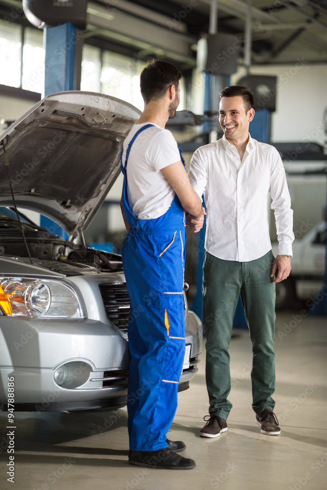 smiling auto mechanic and client shaking hands smiling auto mechanic and client shaking hands