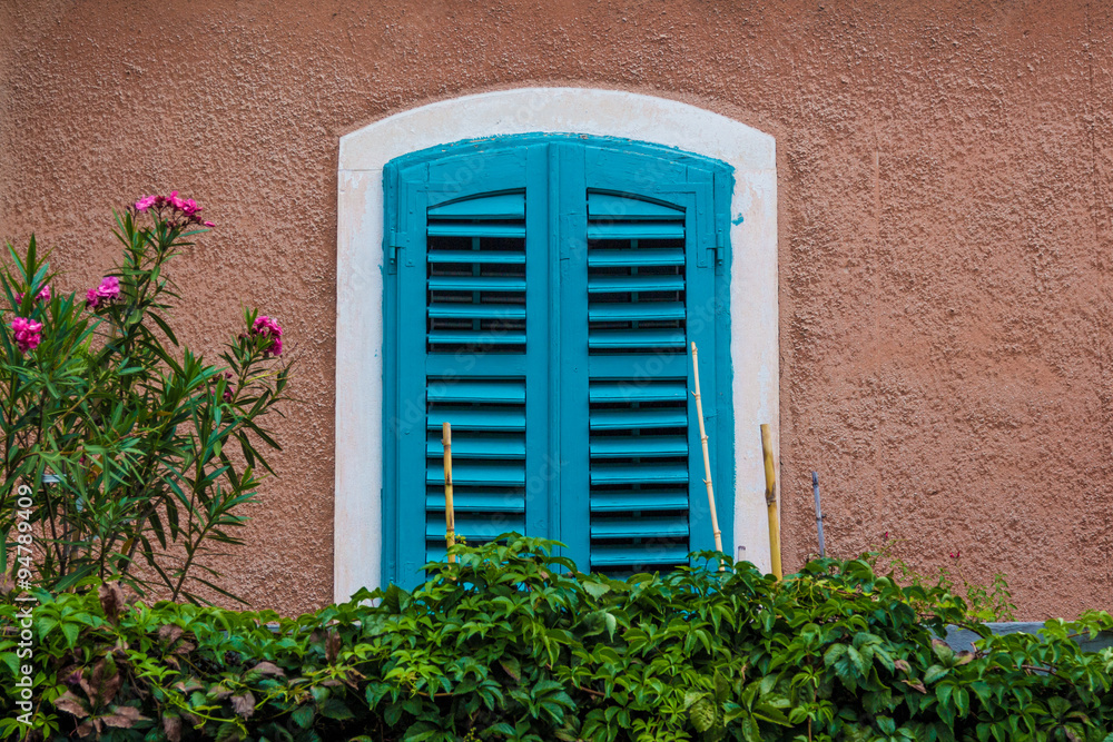 Window closed with blue shutters and surrounded by greenery. Window closed with blue shutters and surrounded by greenery.
