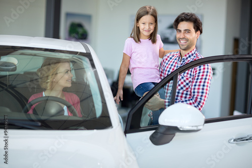 Happy family choosing car in car showroom