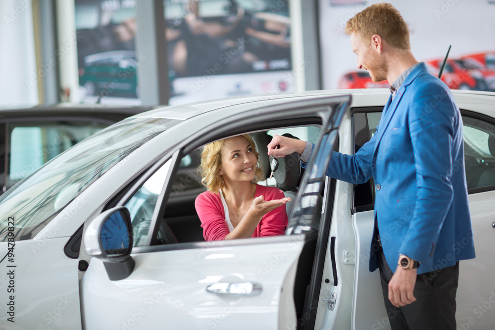 woman receives the keys to a new car from a sales manager woman receives the keys to a new car from a sales manager
