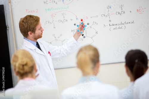 Chemistry teacher hold molecular model and teach students in cla